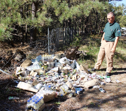 Central Pine Barrens Commission Compliance and Enforcement Officer Mike Lewis with one of the piles of energy drinks in the woods off Speonk-Riverhead Road.